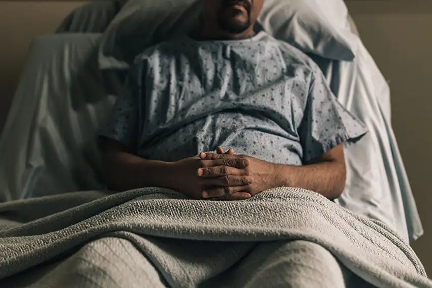 un homme dans son lit d'hôpital les mains croisées