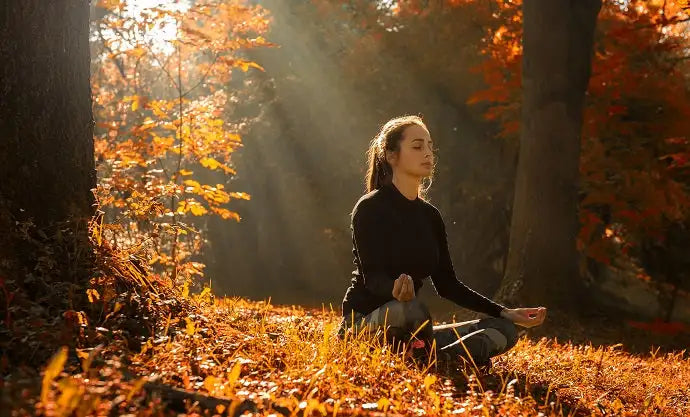 une femme médite dans la foret en automne