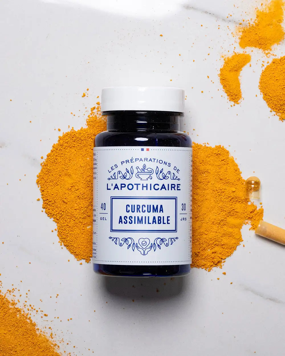 formule curcua assimilable posée sur de la poudre de curcuma avec un fond marbre blanc