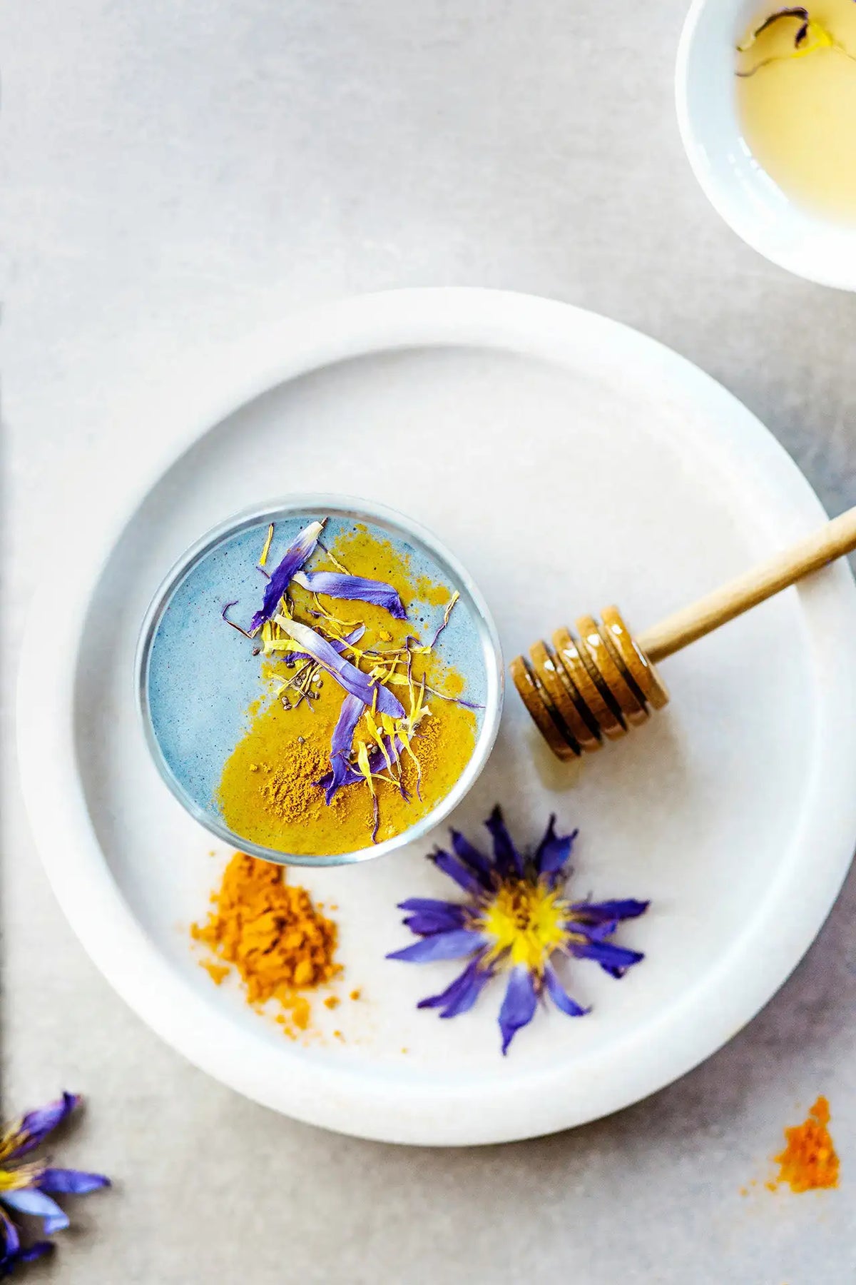 du curcuma en poudre dans une petite assiette avec une cuillère à miel posée à coté